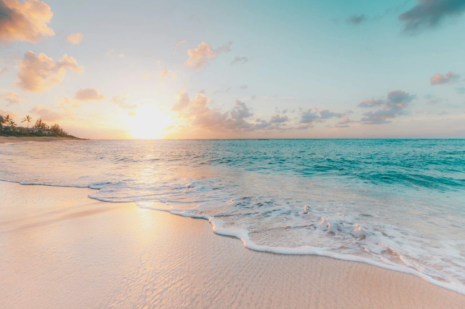 Golden January sunrise over a calm turquoise sea and empty white-sand beach
